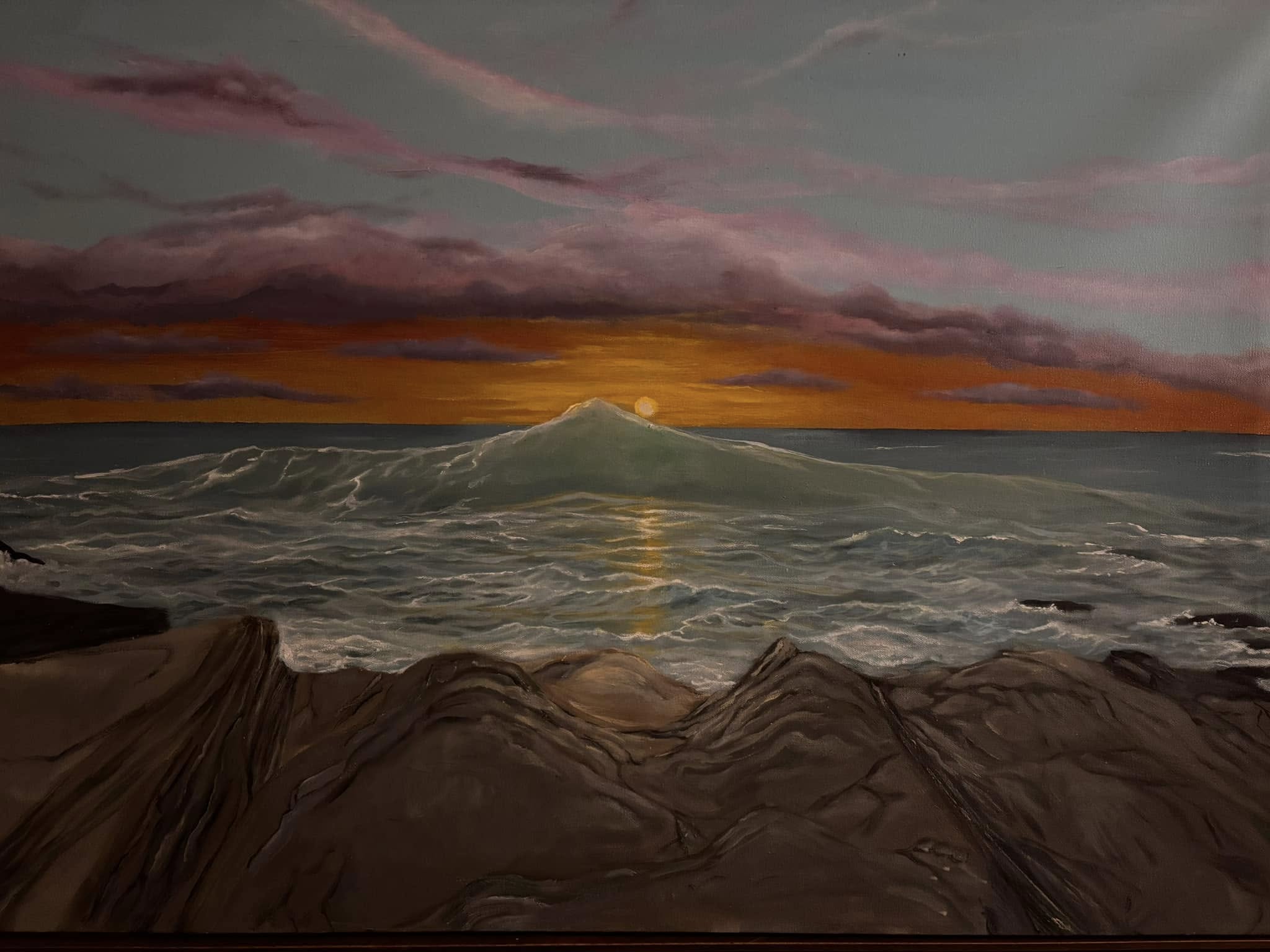 Waves crashing over a rocky cliff at sunset.